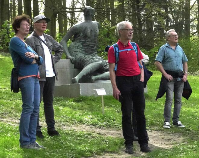 Mehrere Meschen im Wald schauen in eine Richtung.